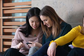 Two students looking at a phone 