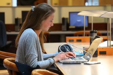 A student studying in Stauffer Library, on the main floor