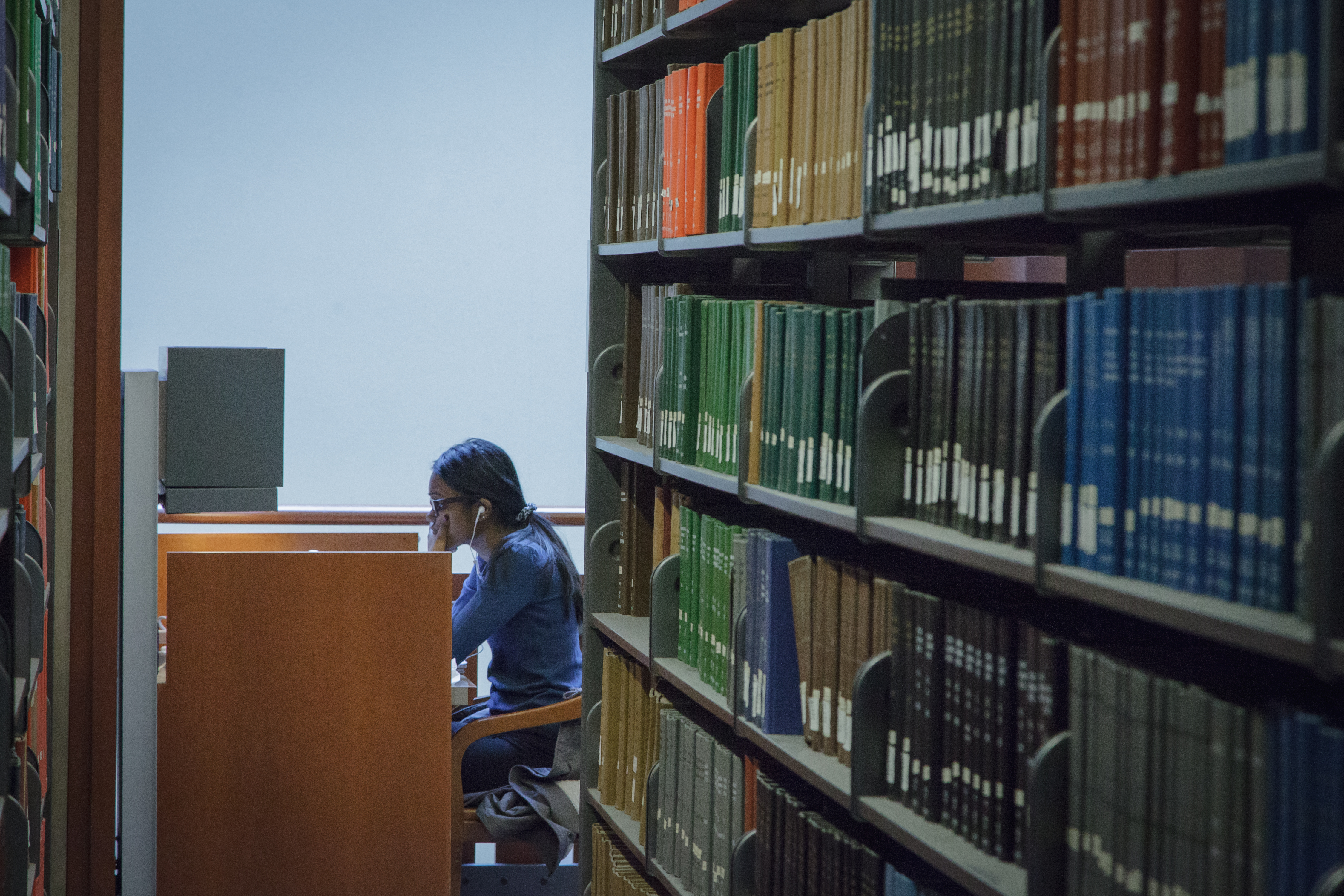 Student studying in a study carrel at the end of a book stack. 