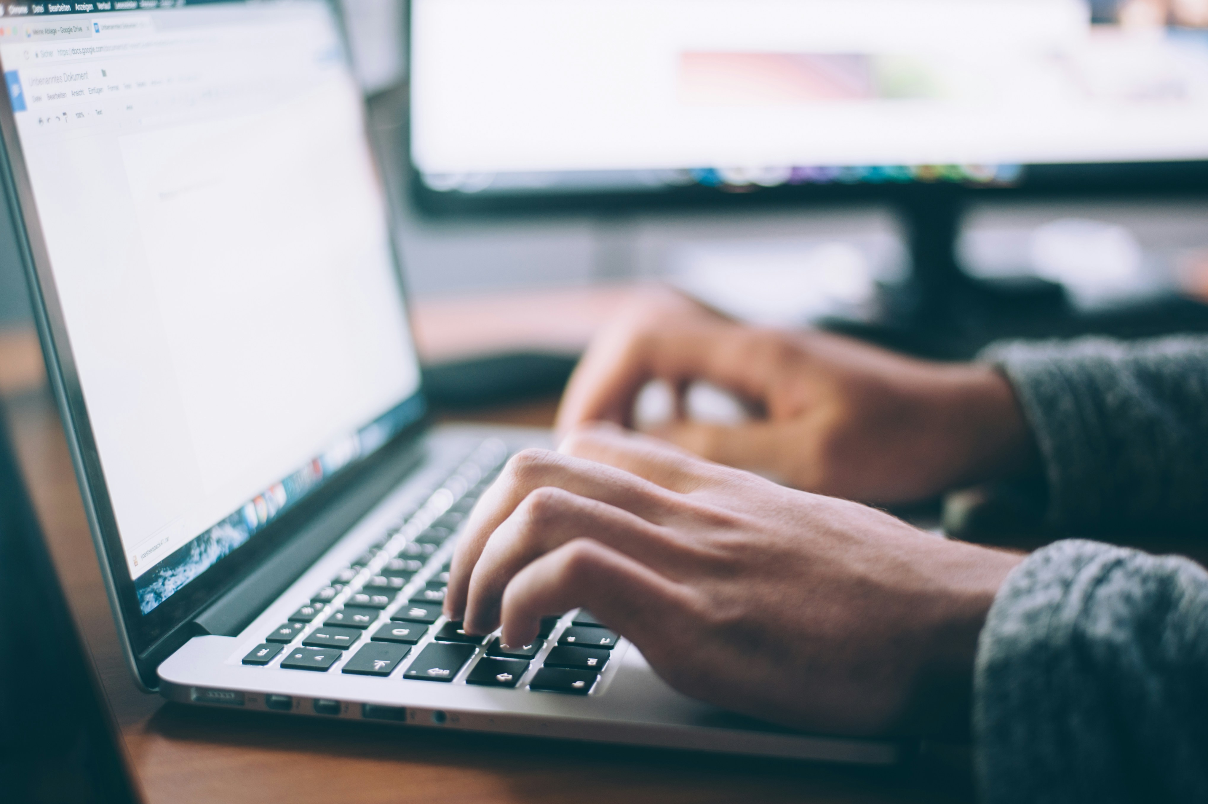 Hands typing at laptop keyboard.