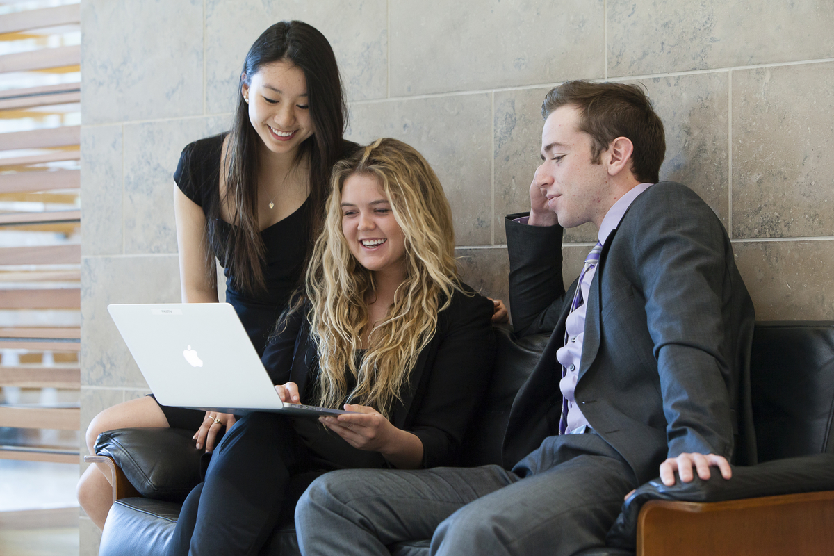 three students working together on a laptop