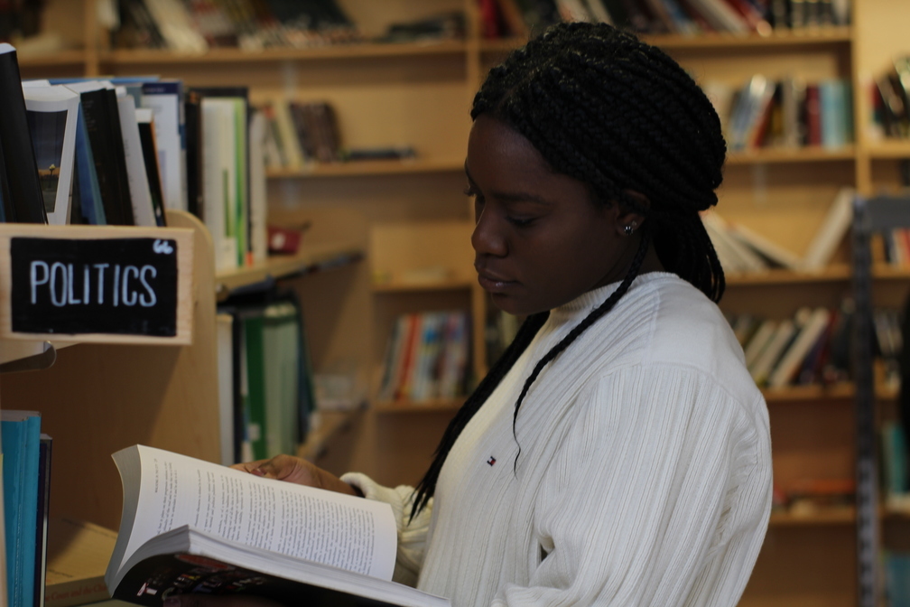 A young woman reads a book in the politics section