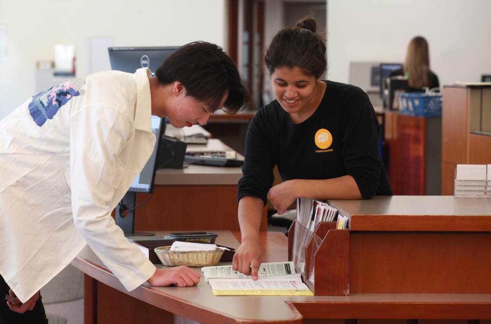 A student helps another at the information services desk