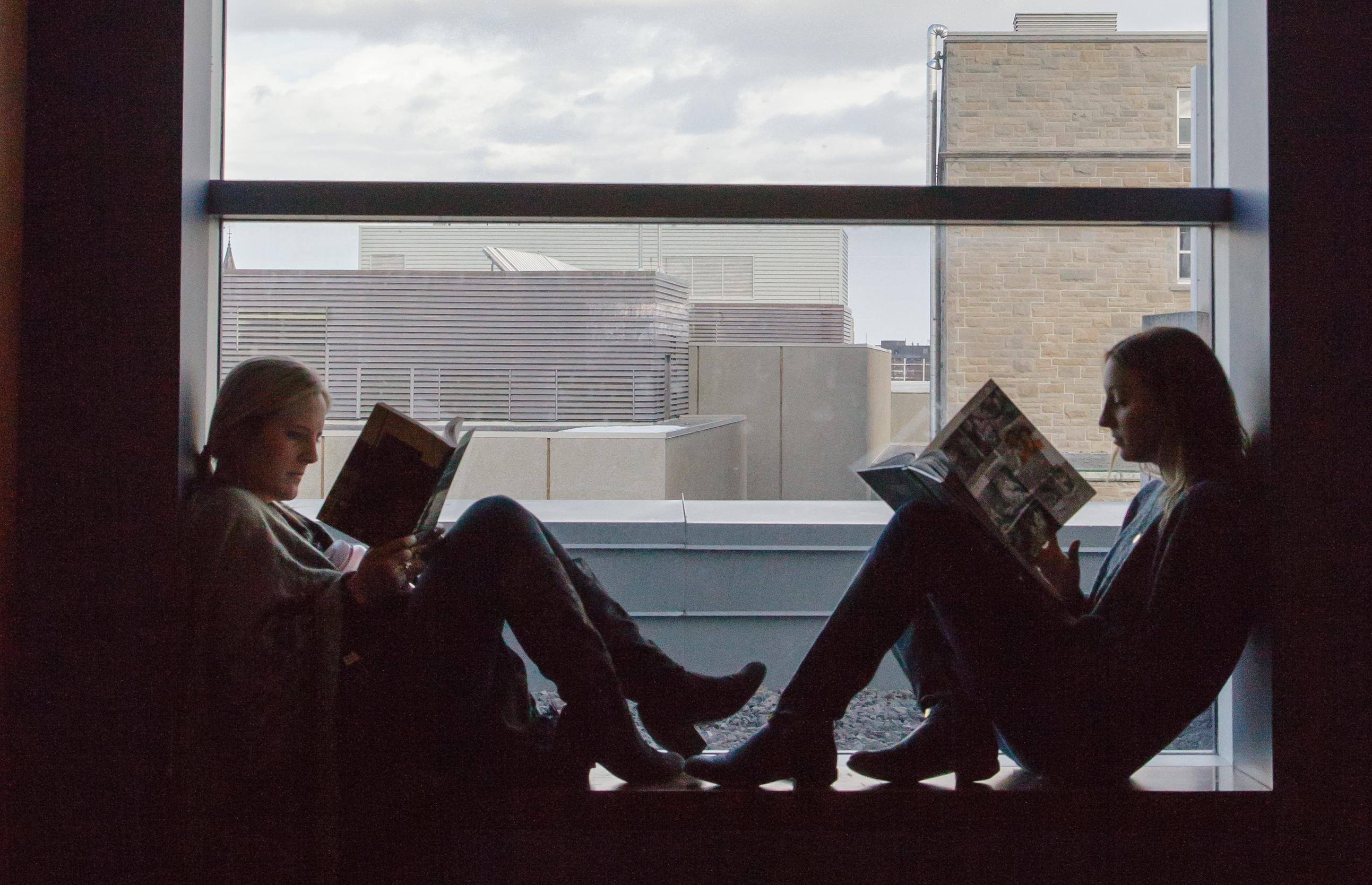 two young women reading in a window sill