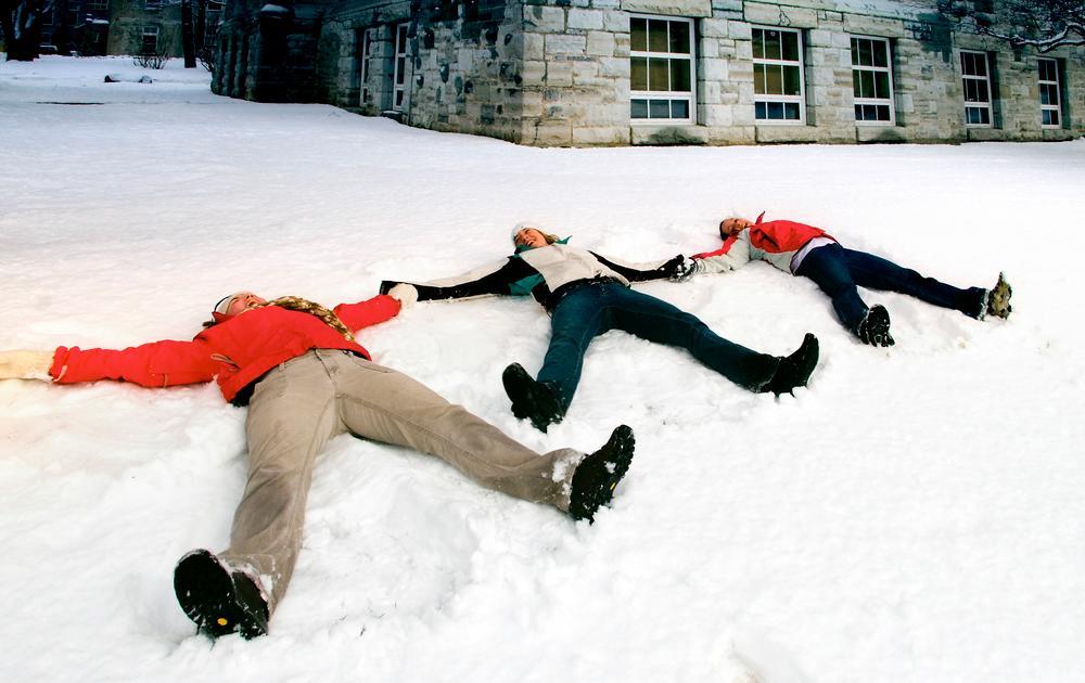 a row of three students making snow angels