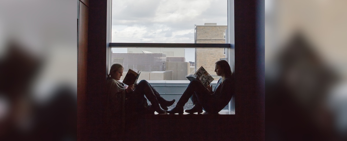 two young women reading in a window sill