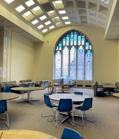 Interior view of the 1966 reading room, featuring study seating, arched ceiling and stained glass window