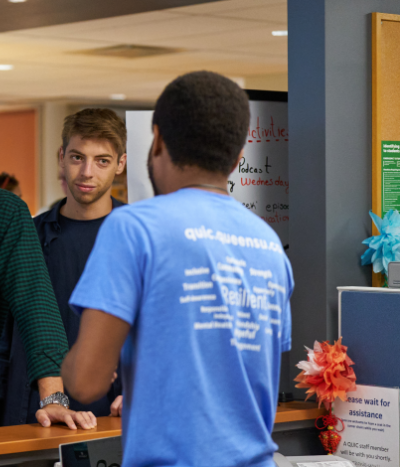 Group of students at a help desk talking to a library representative.