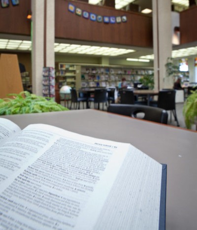 An open book in the foreground with the education library in the background