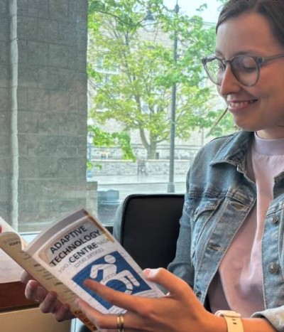A student reads an Adaptive Technology Centre brochure while sitting in a comfortable chair by a window in the Adaptive Technology Centre.