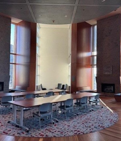 Two long study desks in front of the fire places and floor to ceiling windows in the Alan G. Fireplace Reading Room, Stauffer library.