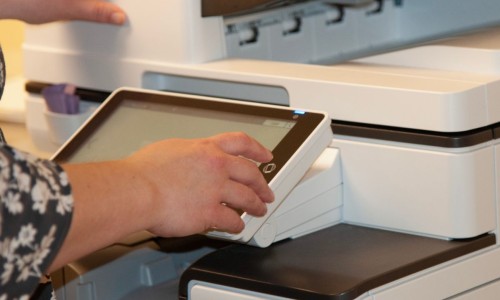 Close up image of a person using the touch screen of a library printer.