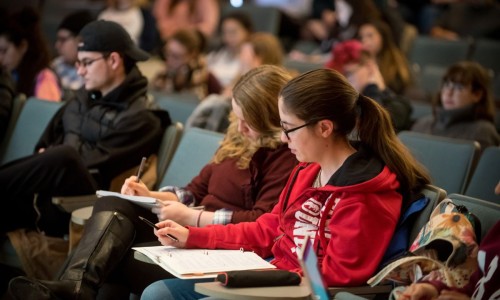 Students sitting in a lecture hall taking notes