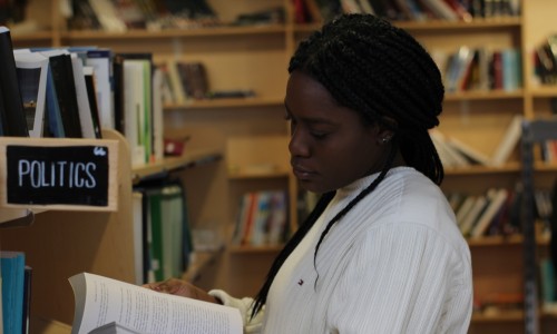 A young woman reads a book in the politics section