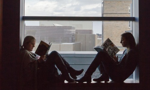 two young women reading in a window sill